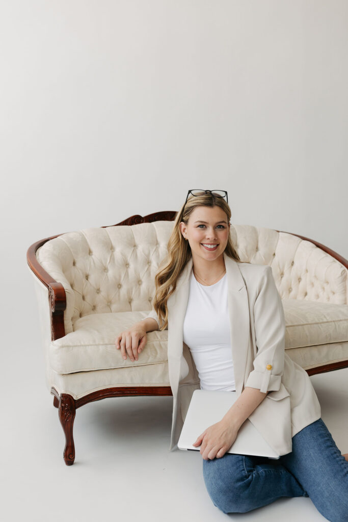 Woman sitting on floor holding a laptop with a couch on the background